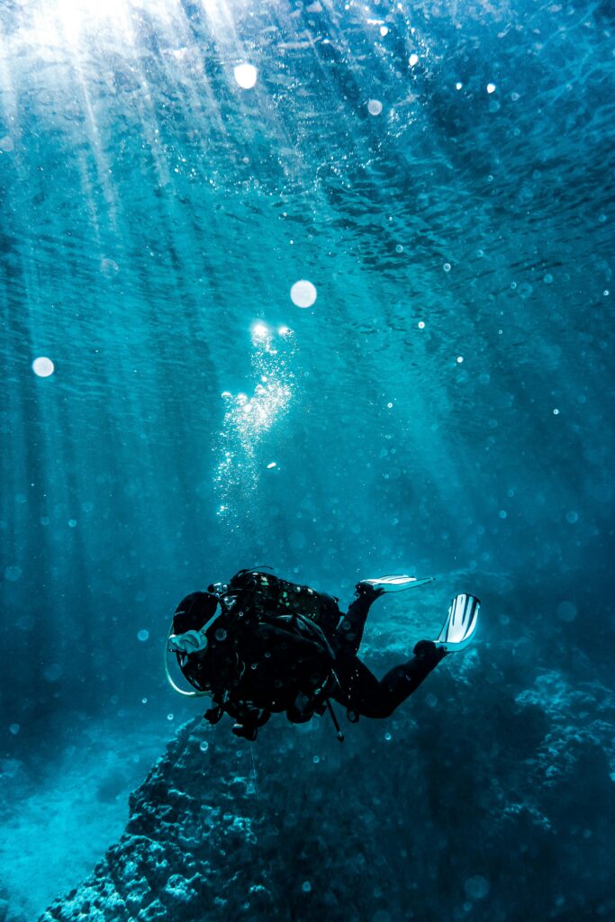 Scuba diver exploring underwater reef in vibrant turquoise waters, capturing marine life beauty.